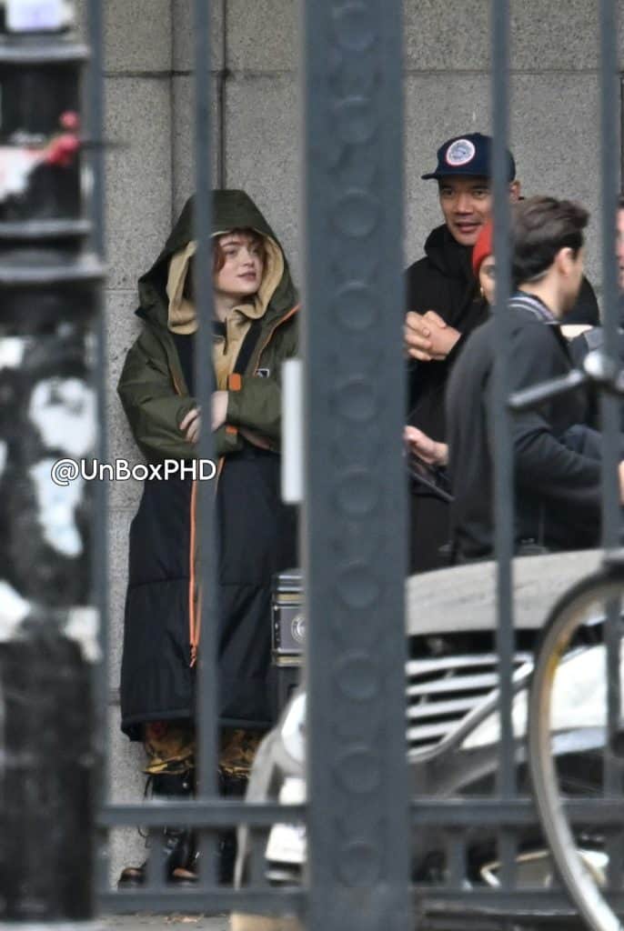 See Sadie Sink on the set of Marvel’s Spider-Man: Brand New Day with Tom Holland in London. She wears military-style boots and yellow pants, while director Destin Daniel Cretton is nearby.